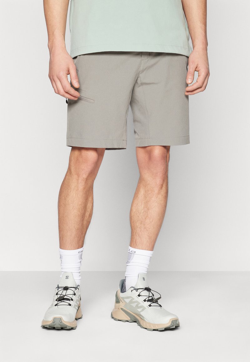 Ljusgrå shorts med rak front, sidofickor och fållade avslut, parat med ljusa träningsskor och vita strumpor.