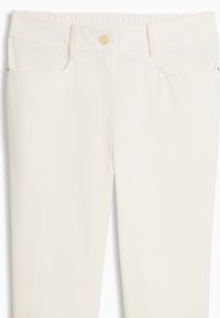 Κρεμ παντελόνι ψηλόμεσο με θηλιές για ζώνη, κλείσιμο με κουμπί μπροστά και πλαϊνές τσέπες, παρουσιάζεται σε λευκό φόντο.