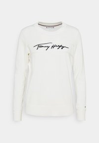 Biała sweatshirt z długim rękawem, wykonana z miękkiego materiału, z haftowanym czarnym logotypem na piersi i ściągaczami przy nadgarstkach.