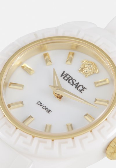 Versace DVONE Uhr mit einem weißen Silikonband, goldenen Akzenten, einem weißen Zifferblatt, goldenen Stundenmarkierungen und einem Medusa-Logo in der 12-Uhr-Position.