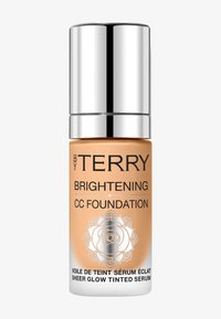 CC-Foundation in einer transparenten Glasflasche. Helles Orange mit fettem schwarzen Text und einem silbernen Deckel. Das Etikett zeigt ein Rosendesign.