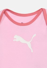 Ροζ βρεφικό φορμάκι με πιο σκούρο ροζ περίγραμμα γύρω από τη λαιμόκοψη και λευκό λογότυπο αλματώδους πούμα στο στήθος.