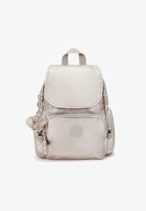 Mochila fabricada con tela brillante de color beige claro, con cierre de solapa. Cuenta con un bolsillo delantero, detalles con cremallera y un charm con una figura de peluche.