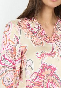 Blouse légère à motifs présentant des designs paisley rose, orange et gris ; col froncé ; fermeture à boutons ; texture douce et lisse.