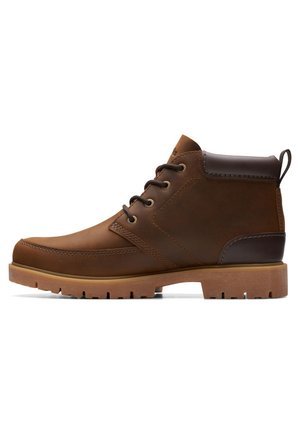 Botas de cuero marrón hasta el tobillo con un diseño resistente, paneles texturizados, punta redonda y suela de goma con ranuras de tracción.