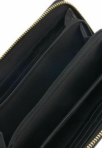 Portafoglio nero con chiusura a zip, dotato di più scomparti e slot per carte in un interno in tessuto liscio. Dettagli in oro sulla zip visibili.