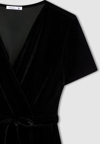 Czarna aksamitna sukienka z głębokim dekoltem w kształcie literki V, krótkimi rękawami i wiązaniem w pasie. Miękka tekstura o gładkim wykończeniu; zaprojektowana z myślą o dopasowanej sylwetce.