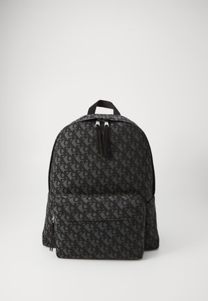 Zaino in tessuto nero con un motivo logo ripetitivo, parte superiore arrotondata, doppie cerniere e una tasca frontale con cerniera. Materiale testurizzato.