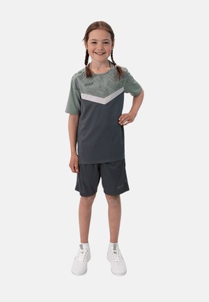 Tenue de sport grise composée d'un haut à manches courtes avec un motif géométrique et d'un short assorti, associé à des baskets blanches.