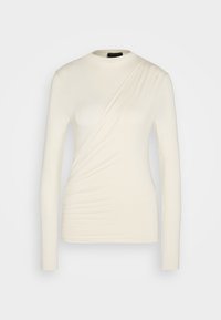 Långärmad topp i elfenben med en asymmetrisk draperad design, mjukt texturerat tyg och insamlad sidodetalj för en figurnära silhuett.