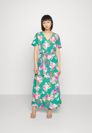 Vestido maxi floral em verde, com flores rosas e brancas, mangas curtas, decote em V e um laço na cintura para ajuste. Textura de tecido suave.