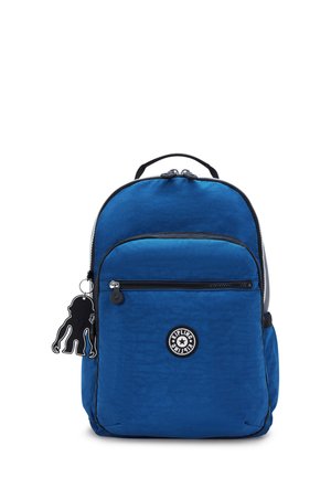 Zaino in nylon blu con tasca frontale con zip, manico superiore, spallacci regolabili e un ciondolo in plastica nera attaccato. Logo del marchio circolare al centro.