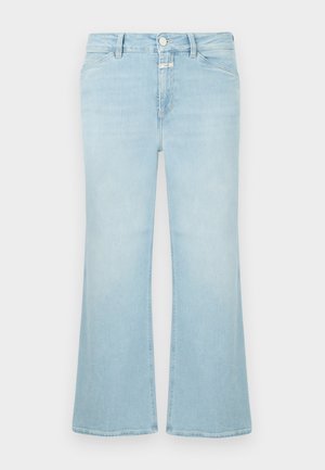 Kremfarget strikkegenser med diamantmønster, lyseblå vide jeans, grønne sneakers med svarte striper, og en liten svart veske.