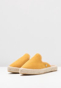 Gula mocka espadrillos med en mjuk textur, slip-on-design och vävd jutesula. Har en liten metallisk accent på sidan.