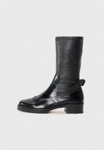 Zwarte enkelboot met een soepele leren bovenkant, brogue details, ronde neus en een blokhak van gemiddelde hoogte. Voorzien van een zachte, gestructureerde schacht.