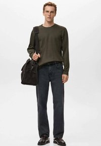 Donkergroen shirt met lange mouwen, donkergrijze spijkerbroek en bruine leren schoenen. Draagt een zwarte schoudertas met een riem en een voorvak.