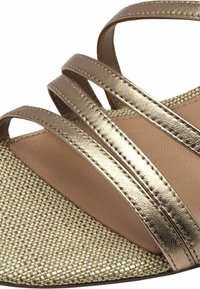 Metalliset kultaiset sandaalit, joissa on kolme kapeaa hihnaa, teksturoidut kudottu pohjat ja sileä beige vuori.