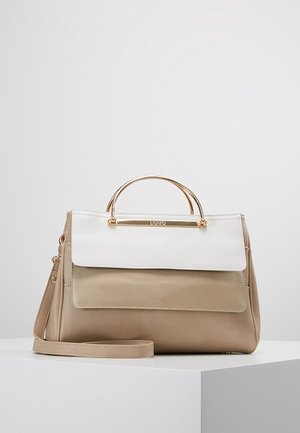Sac à main en cuir beige et blanc avec poignée dorée et bandoulière détachable posé sur une surface blanche.