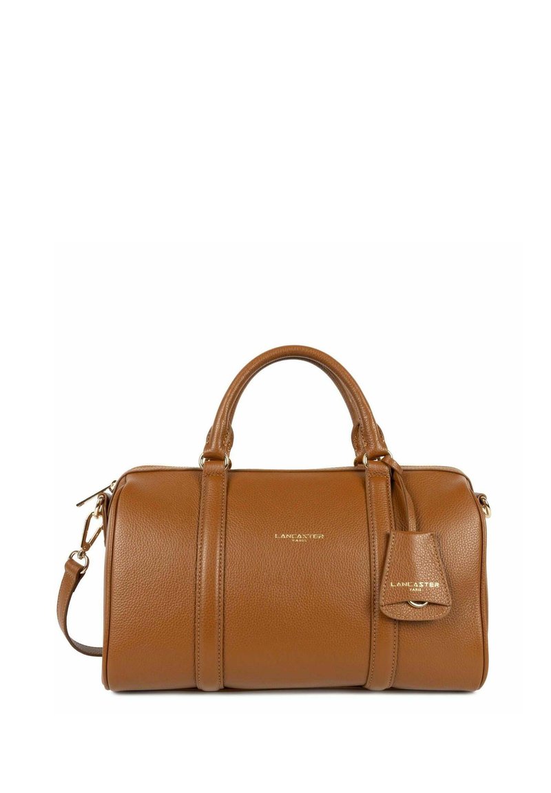 Sac à main en cuir tan avec deux poignées courtes et une bandoulière réglable. Doté d'une fermeture éclair et d'une petite étiquette avec le logo.