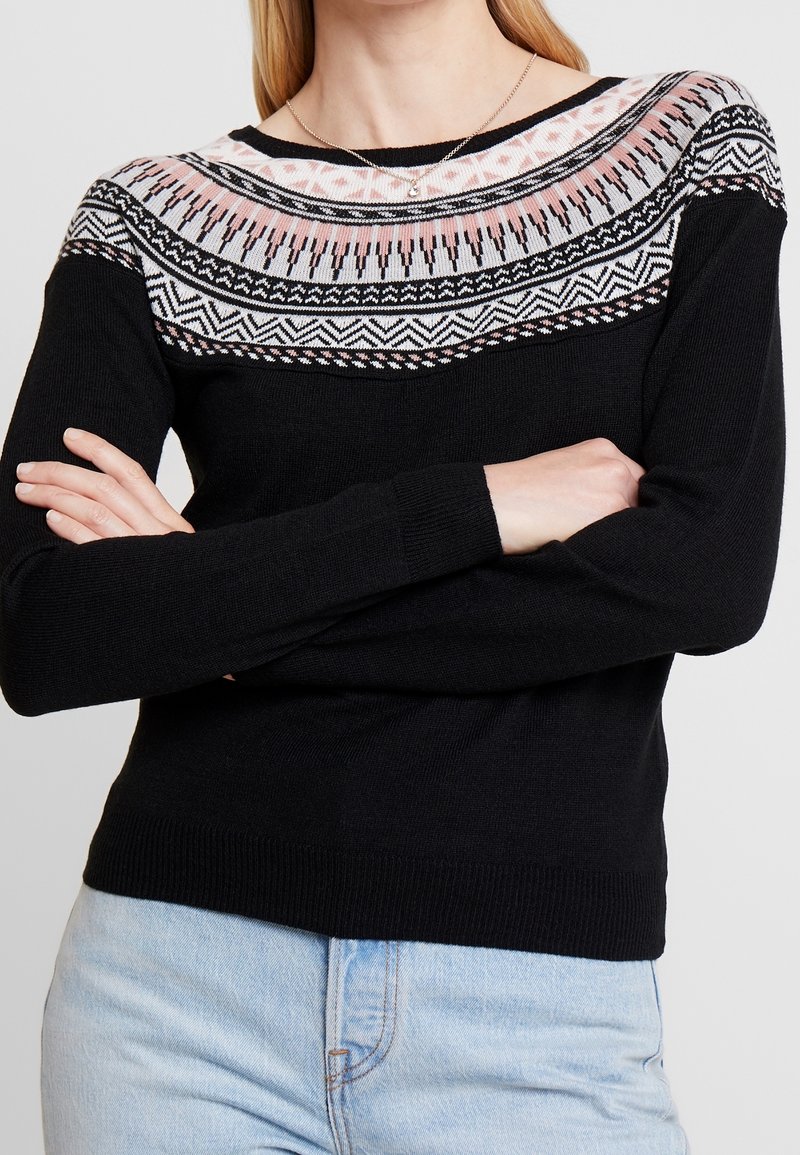 Svart tröja med ett färgglatt geometriskt mönster längs halslinningen, med långa ärmar och ribbade mudd och nederkant.