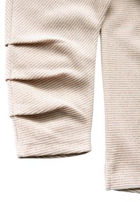 Manica di maglione a coste color beige chiaro con strisce testurizzate e dettagli arricciati al polsino. Tessuto morbido e lavorato a maglia con un aspetto strutturato.