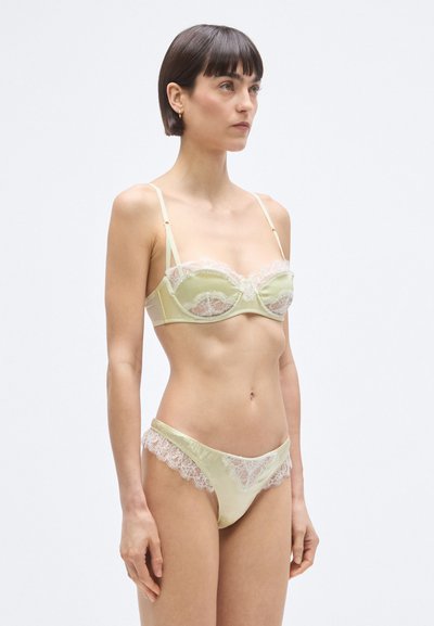 Világoszöld szatén fehérnemű szett, amely egy csipkés részletekkel és állítható pántokkal ellátott melltartóból, valamint hozzáillő, csipkével díszített bugyiból áll.