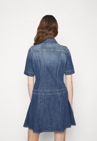 Vestido de denim con mangas cortas, cuello, cuerpo ajustado y falda acampanada. Presenta detalles de costura y un color azul oscuro.