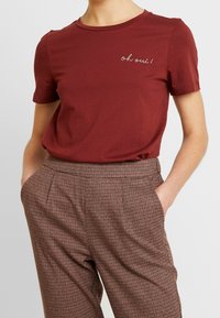 Bordeaux bomulds t-shirt med korte ærmer og rund hals, med hvid broderet tekst "oh oui!" på venstre side.