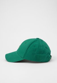 Căciulă de baseball din bumbac verde, cu o margine curbată, curea ajustabilă și un mic accent auriu pe partea laterală. Textură netedă, design clasic.