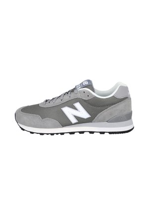 Zapatilla gris New Balance con logo blanco "N", parte superior de malla y ante, cuello acolchado blanco y suela negra texturizada mirando hacia la derecha.