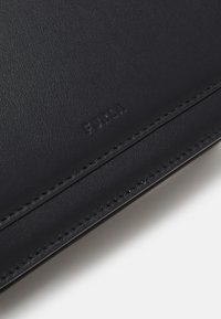 Černá kožená peněženka s vyraženým logem "FURLA", s hladkým povrchem, precizním stehem a minimalistickým designem.