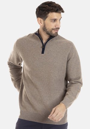 Pull beige zippé avec un motif en tricot texturé. Il présente un bord de col bleu marine et des poignets et ourlet côtelés. Finition du tissu lisse.