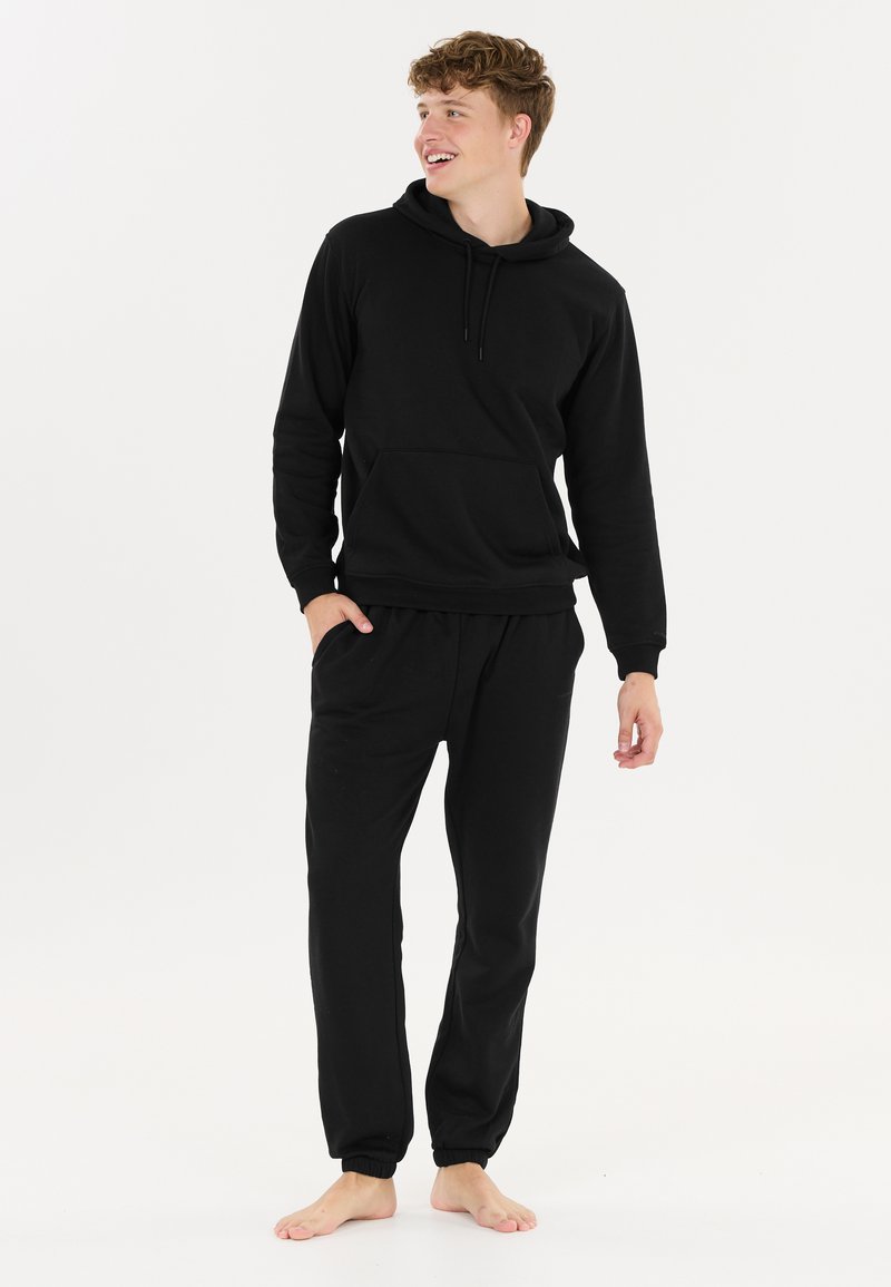 Zwarte katoenen hoodie met bijpassende joggingbroek. De hoodie heeft een voorzak en een trekkoord, terwijl de joggingbroek een elastische tailleband heeft.