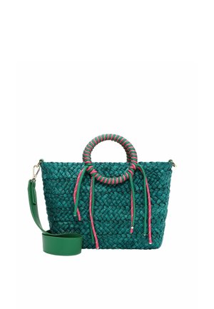 Bolso tejido en color verde azulado con asa circular envuelta en rosa y verde azulado, borlas colgantes en rosa y verde azulado, y una correa de hombro verde desmontable.