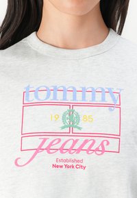 Šedé bavlnené tričko s multicolor textom: "tommy" svetlomodrej farby, "jeans" ružovej farby a "Established New York City" červenej farby, s logom.