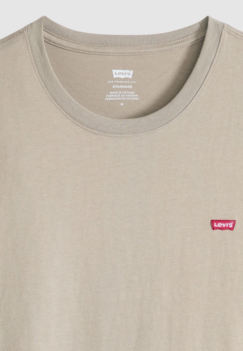 Beige bomullst-shirt med rund halsringning och korta ärmar, med en röd Levi's-logotyp på vänster bröst.