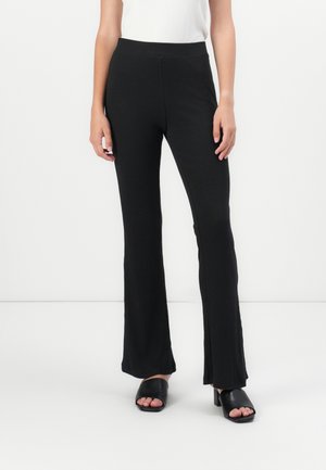 Black flared pants made of ribbed fabric, featuring a high waistband and split hem details, paired with black open-toe heels.