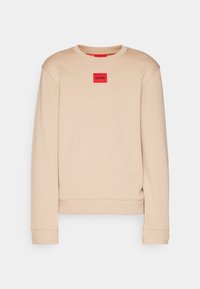 Felpa beige con colletto rotondo, polsini e orlo a coste. Presenta un'etichetta rettangolare rossa con il logo "HUGO" sul petto. Texture morbida.