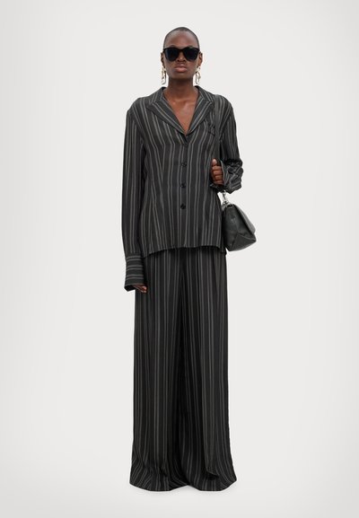 Black and gray striped oversized suit, featuring a button-down jacket and wide-legged pants, paired with a small bag and sunglasses.