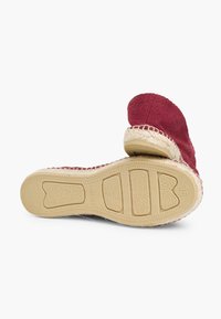Rode textiele espadrille met een verhoogd, gestructureerd design en een geweven jute rand, voorzien van een rubberen zool met ribbels en maatmarkeringen.