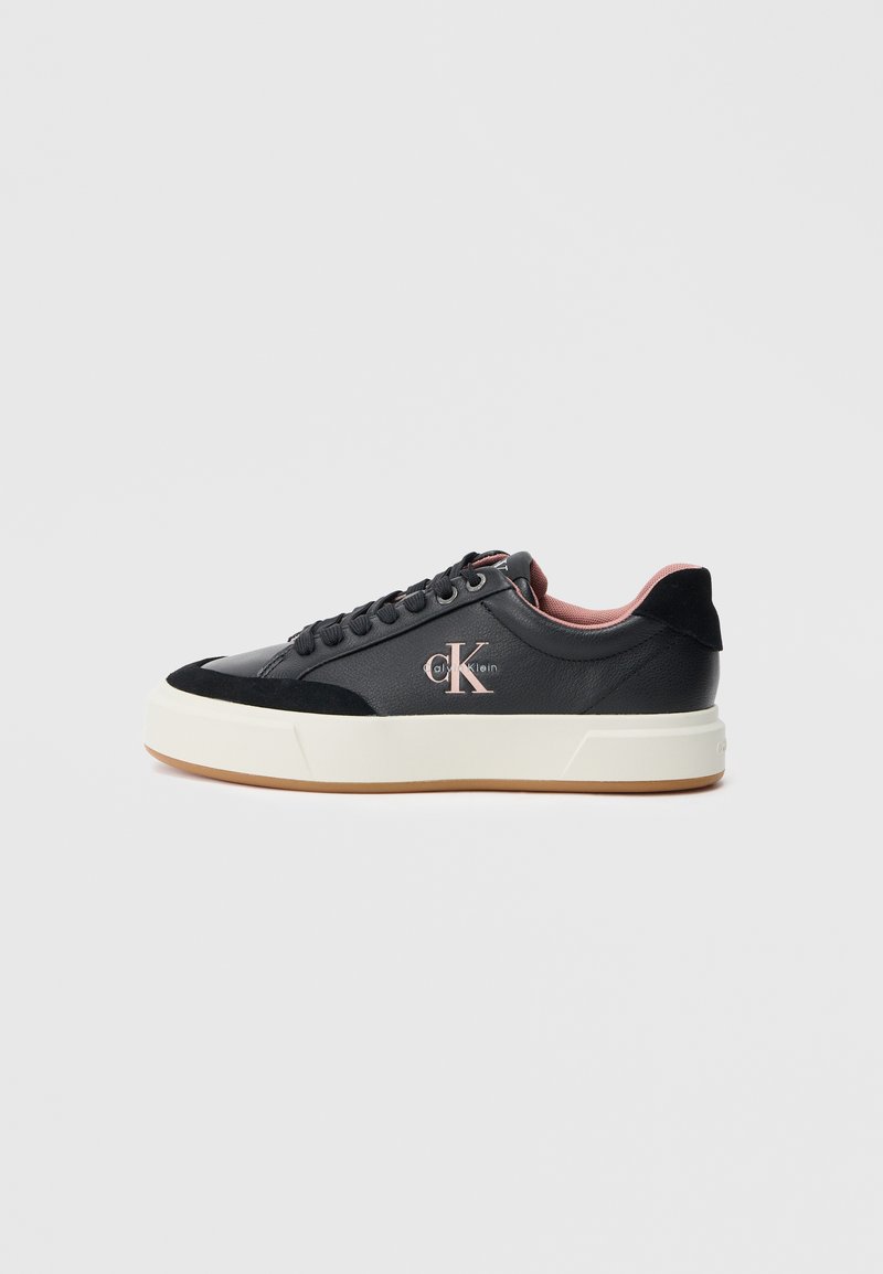 Sapatilha preta com parte superior em couro liso, detalhes em camurça, pormenores rosa claro e uma sola branca espessa. Apresenta atacadores redondos e logotipo.