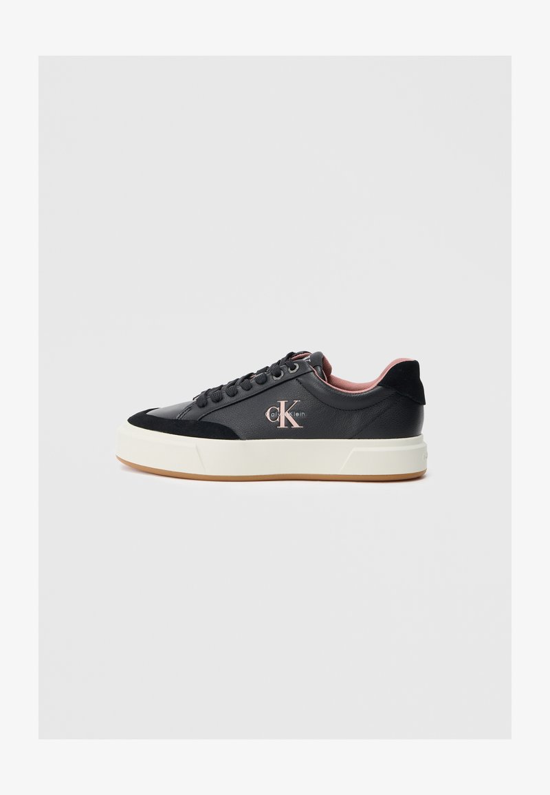 Sapatilha preta com parte superior em couro liso, detalhes em camurça, pormenores rosa claro e uma sola branca espessa. Apresenta atacadores redondos e logotipo.