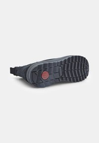 Czarne zamszowe buty z teksturowaną gumową podeszwą. Do wyróżniających cech należy czerwony okrągły akcent oraz wzór bieżnika zapobiegający poślizgom.