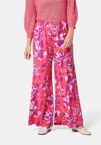 Pantalons larges floraux de couleur rose vif, ornés de grandes fleurs violettes et blanches, avec une taille élastique pour plus de confort et de facilité à porter.