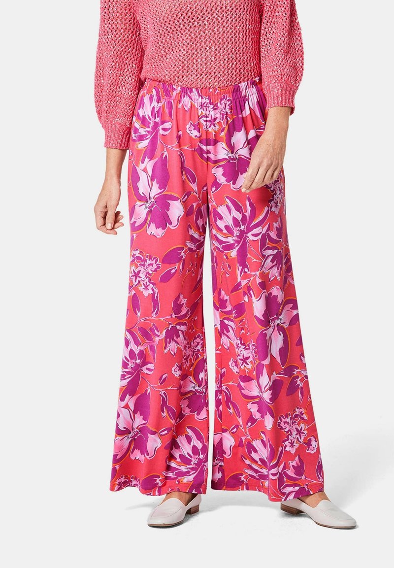 Pantalons larges floraux de couleur rose vif, ornés de grandes fleurs violettes et blanches, avec une taille élastique pour plus de confort et de facilité à porter.