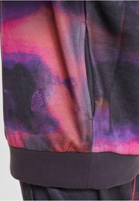 Pullover in morbido tessuto con un motivo gradient di rosa, viola e nero. Caratterizzato da una tasca laterale e polsini e orlo a costine. Piccolo logo decorativo.