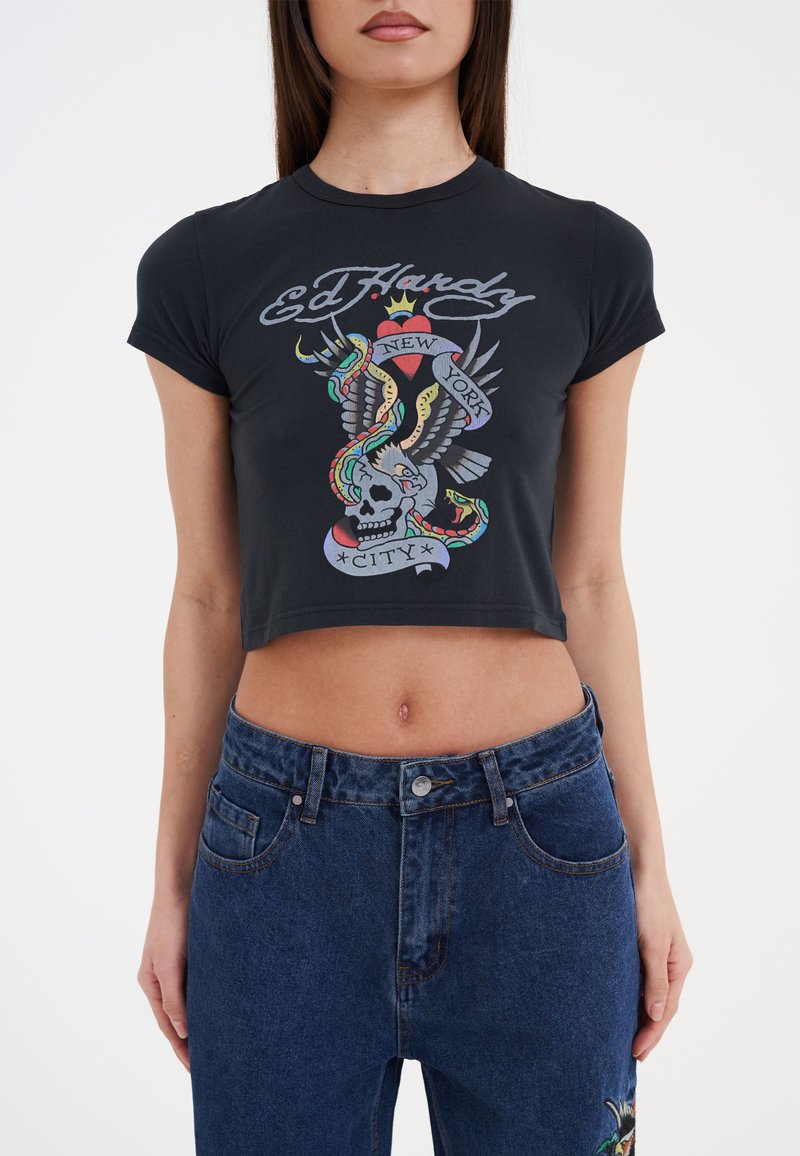 Mustat lyhyet hihoiset t-paidat, joissa on värikäs graafinen kuva pääkallosta, käärmeistä ja siivistä, sekä teksti "Ed Hardy New York City."