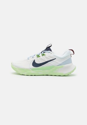 Zapatilla de running Nike blanca y azul claro con suela verde clara, logo azul oscuro, cordones azul claro y tira tira en el talón color granate, vista lateral.