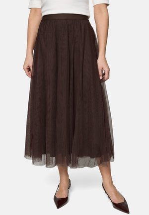 Femme portant une jupe en tulle marron foncé longueur genou, associée à des escarpins slingbacks marron foncé à bout pointu et un haut blanc.