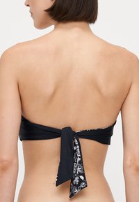 Μαύρο μπικίνι τοπ bandeau με λουλουδάτο σχέδιο και δέσιμο στην πλάτη. Απαλή υφή, απλός σχεδιασμός, επιτρέπει ρυθμιζόμενη εφαρμογή.